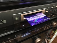 Hands inserting a Minidisc into a sleek portable player in a cozy room.