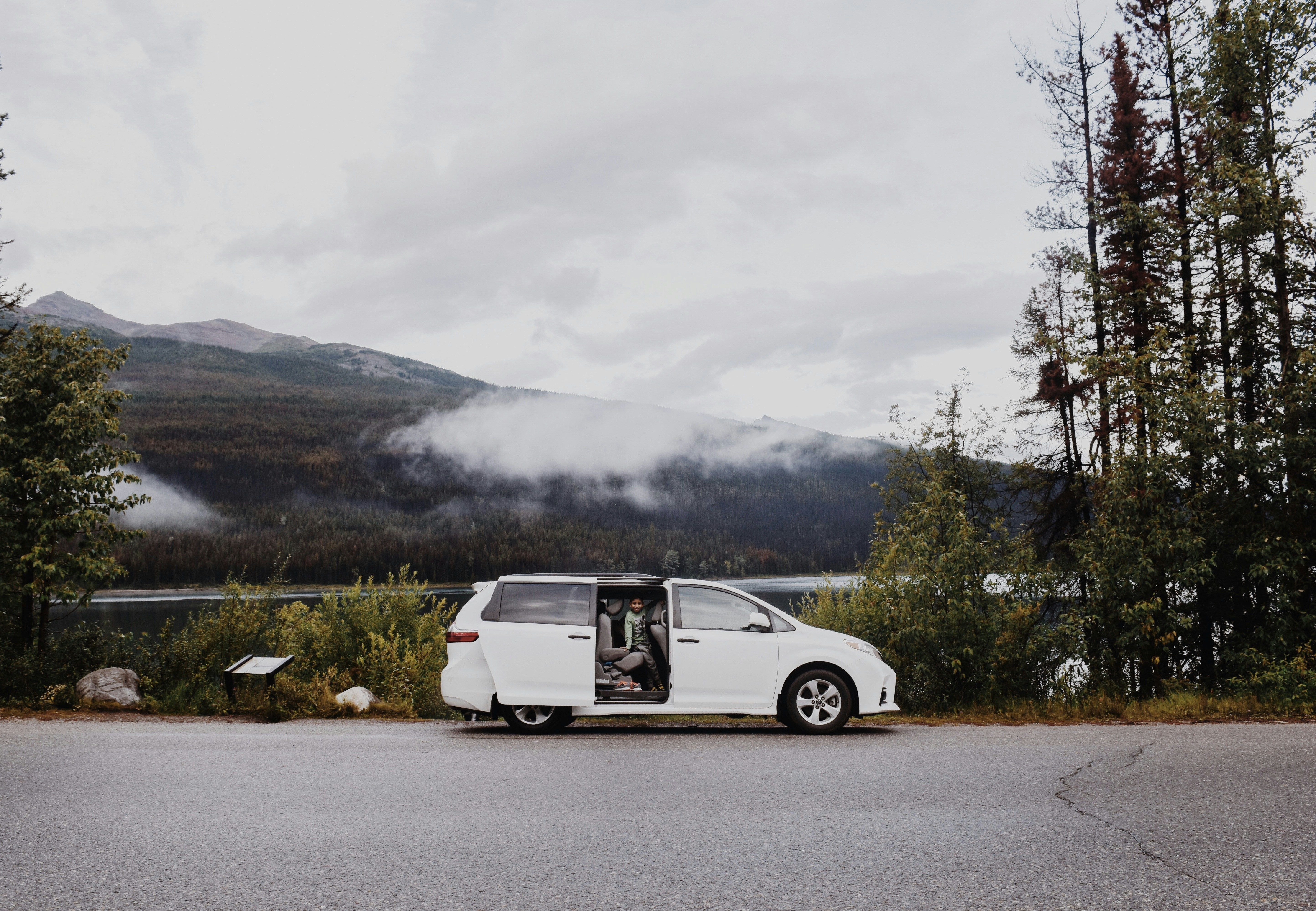 white suv on road near green trees and mountain during daytime