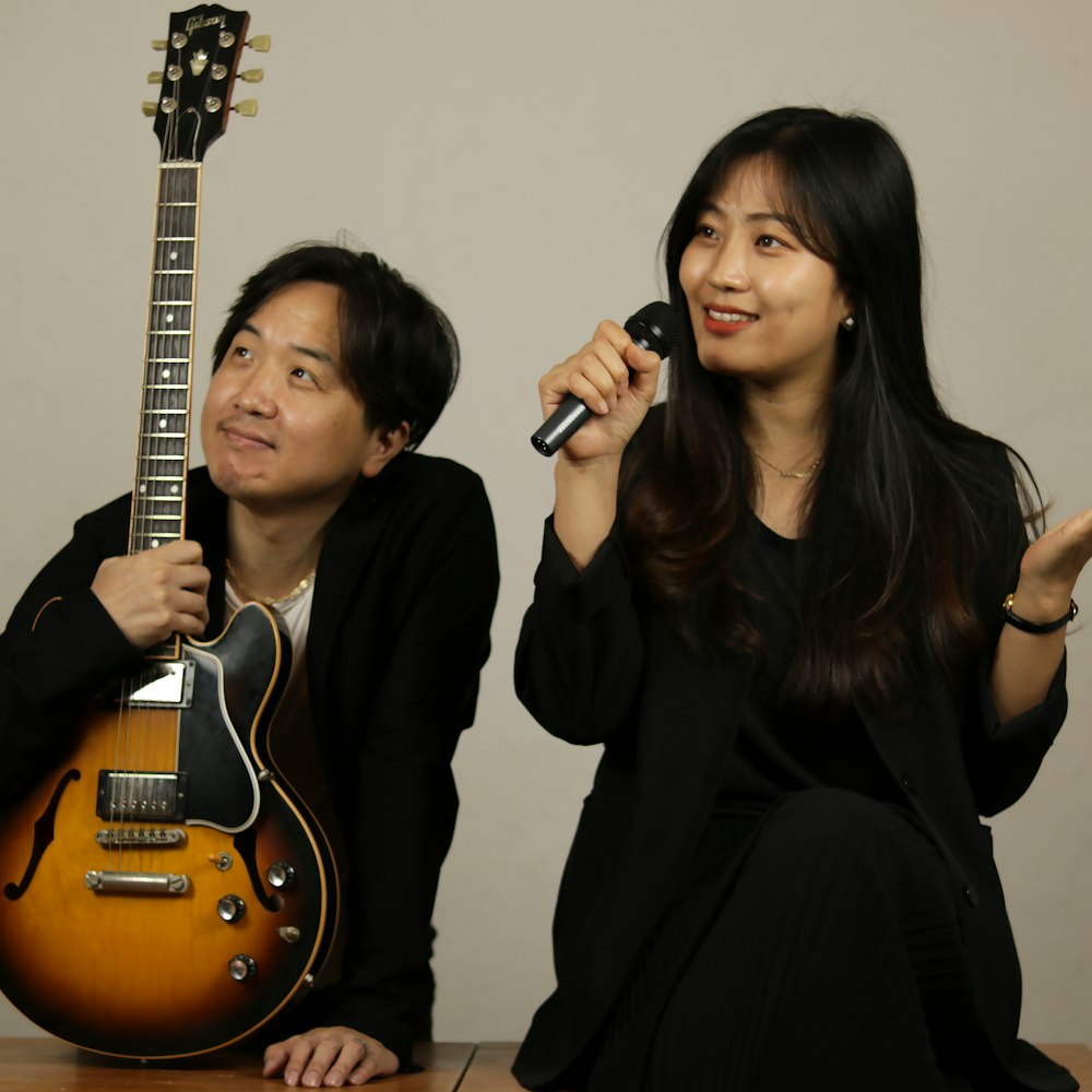 woman in black long sleeve shirt holding brown acoustic guitar