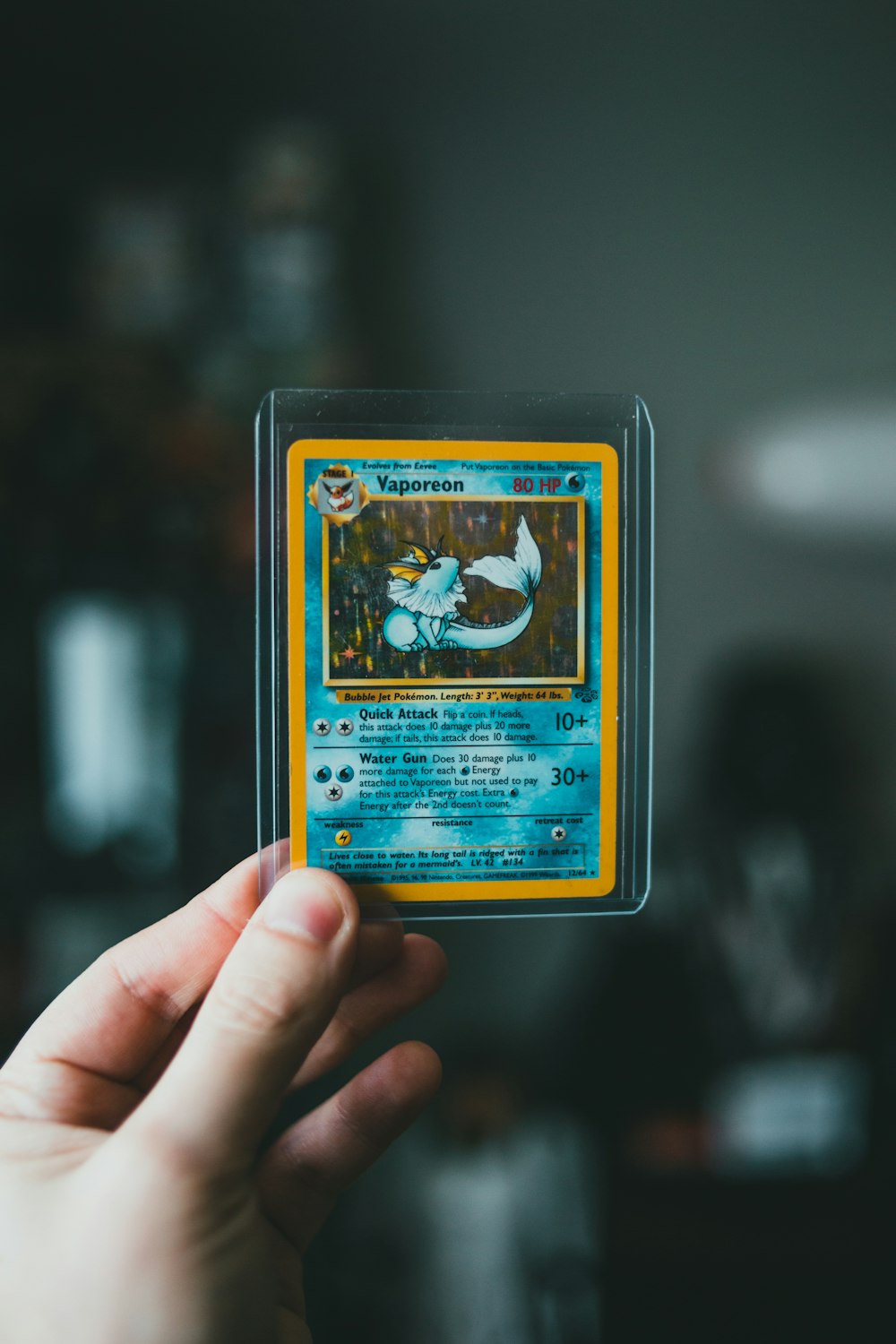 tarjeta coleccionable de pokemon en la mano de las personas