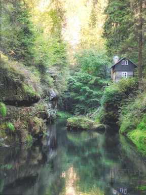 A cozy wooden cabin by a serene river at sunset, inviting calm and relaxation.