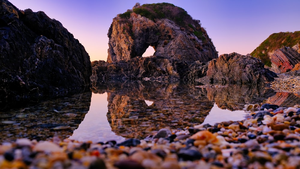 brown rock formation on body of water during daytime