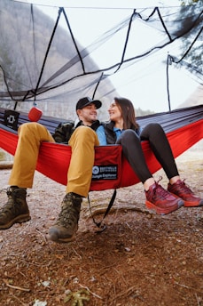 2 women sitting on red hammock