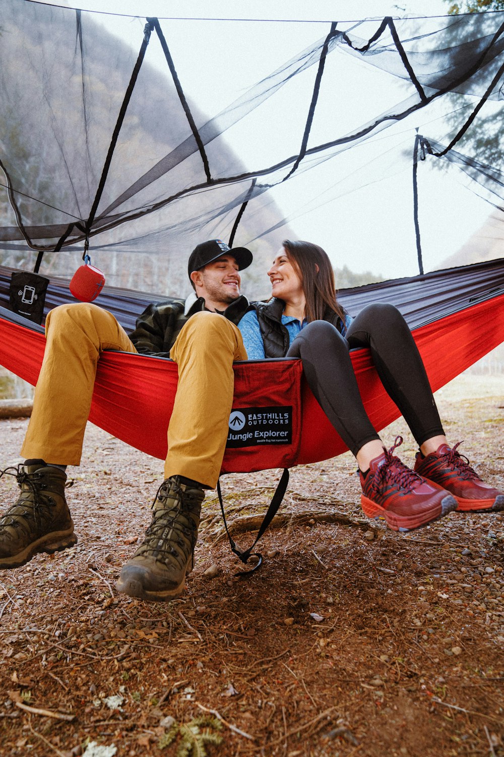 2 women sitting on red hammock