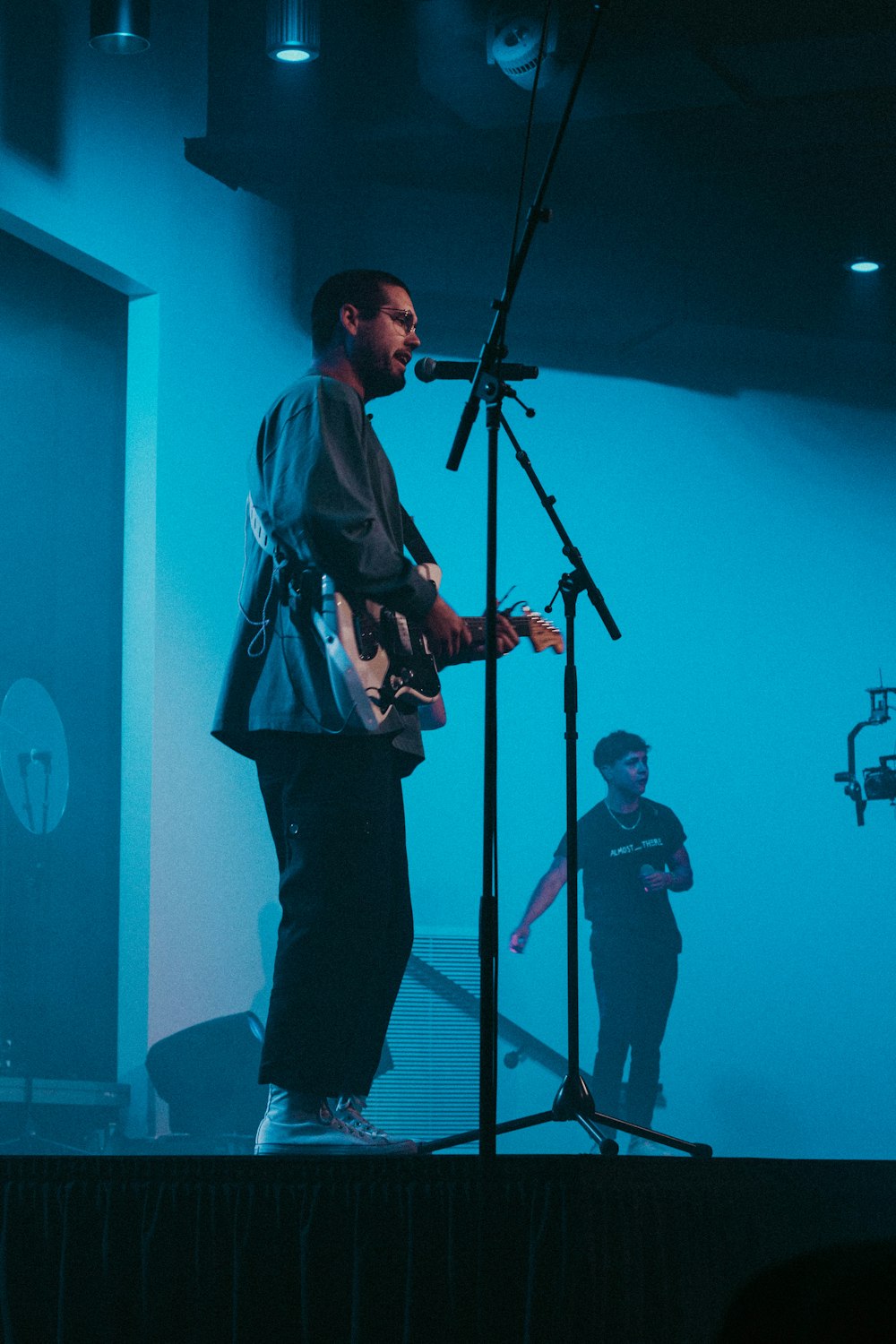 man in black and white jacket playing guitar