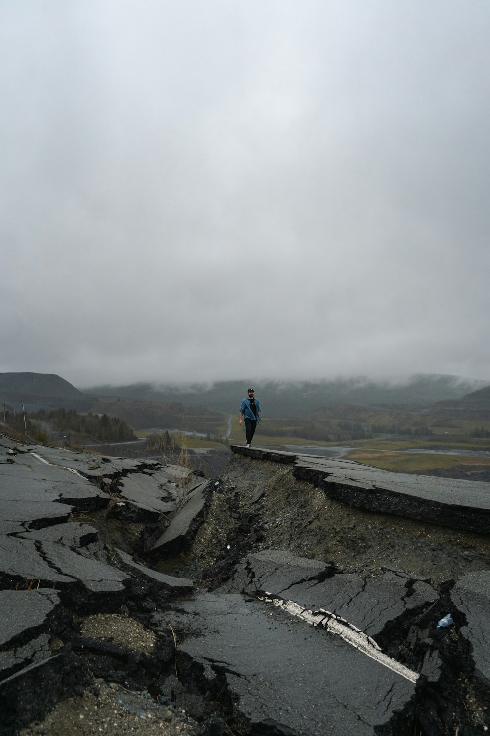 man in blue jacket standing on rock formation during daytime