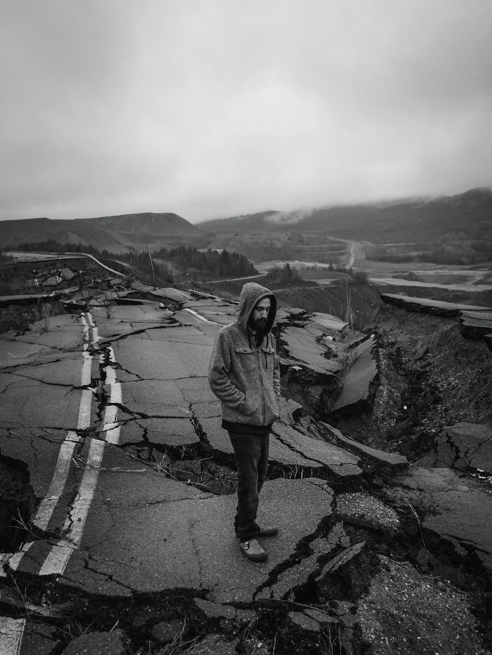 man in gray jacket standing on gray concrete road