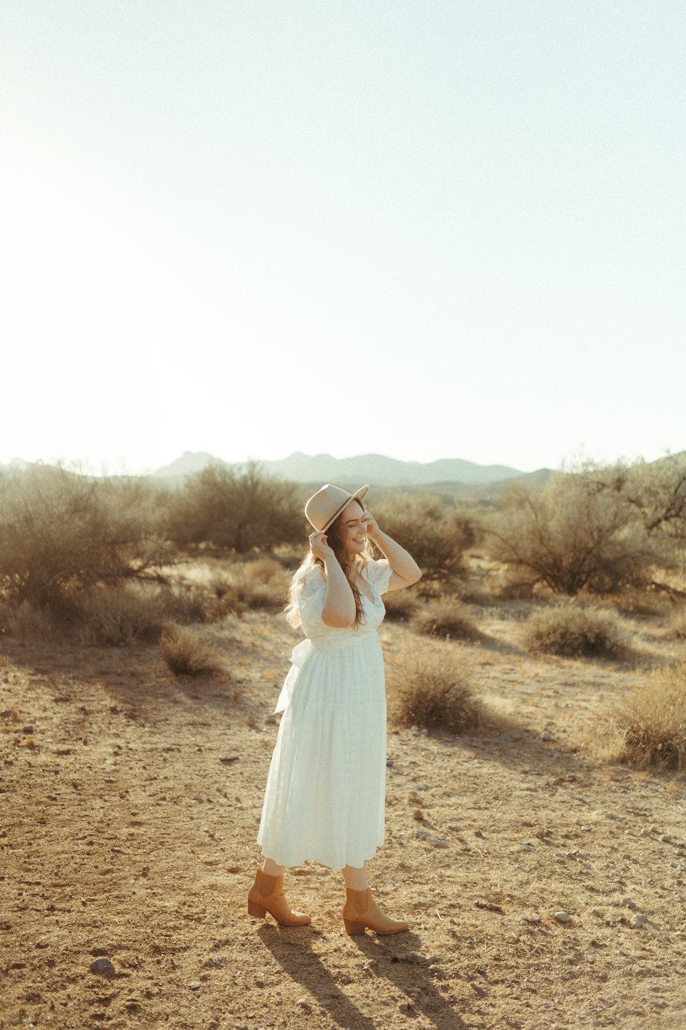 woman in white dress standing on brown grass field during daytime