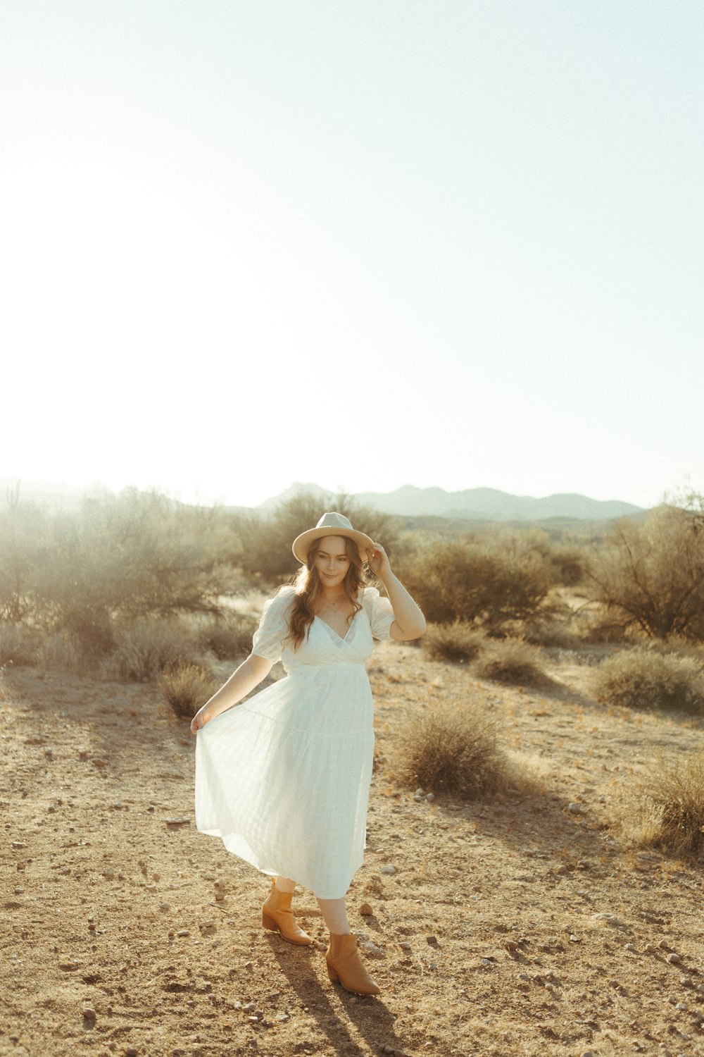 woman in white dress standing on brown grass field during daytime