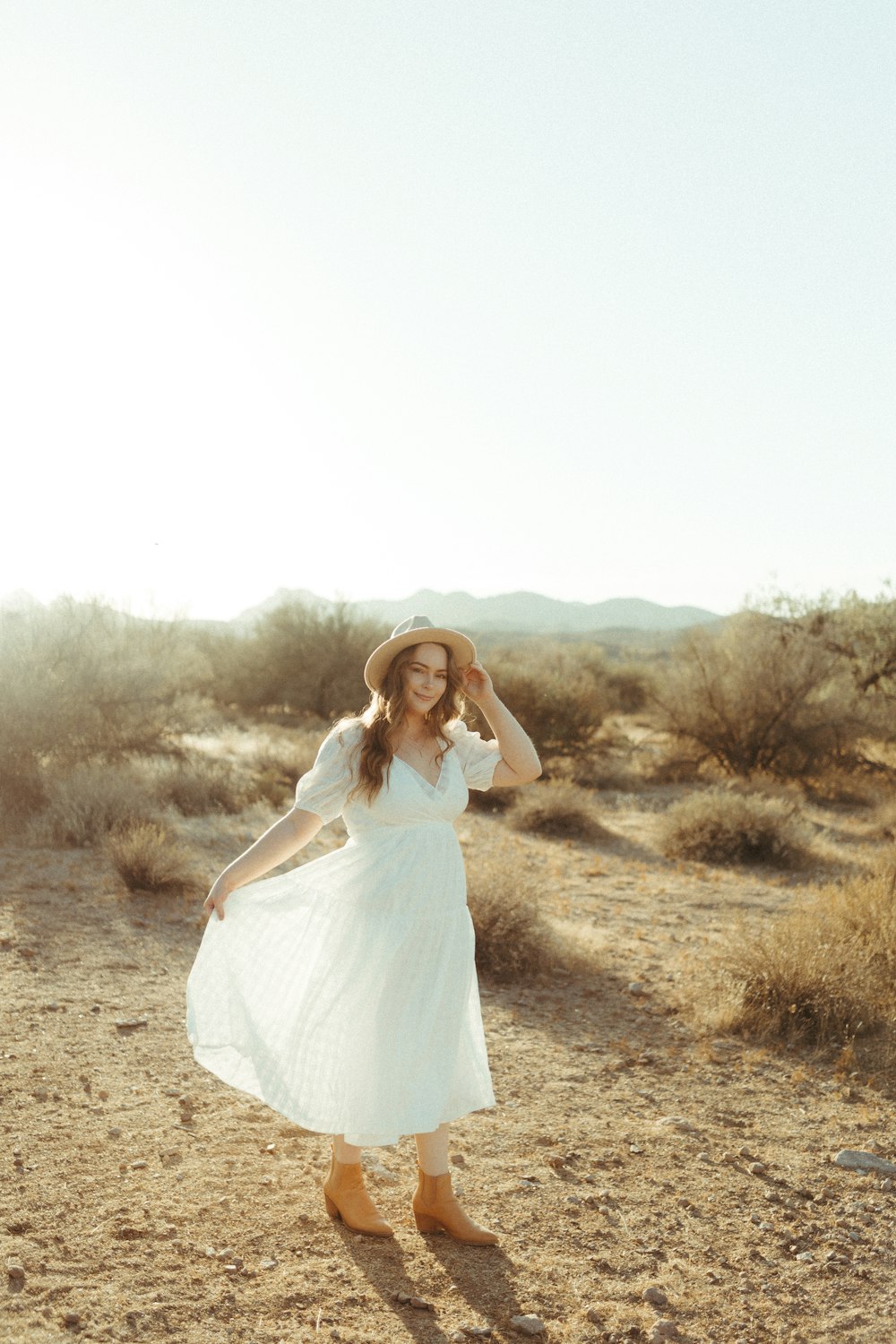 woman in white dress standing on brown grass field during daytime