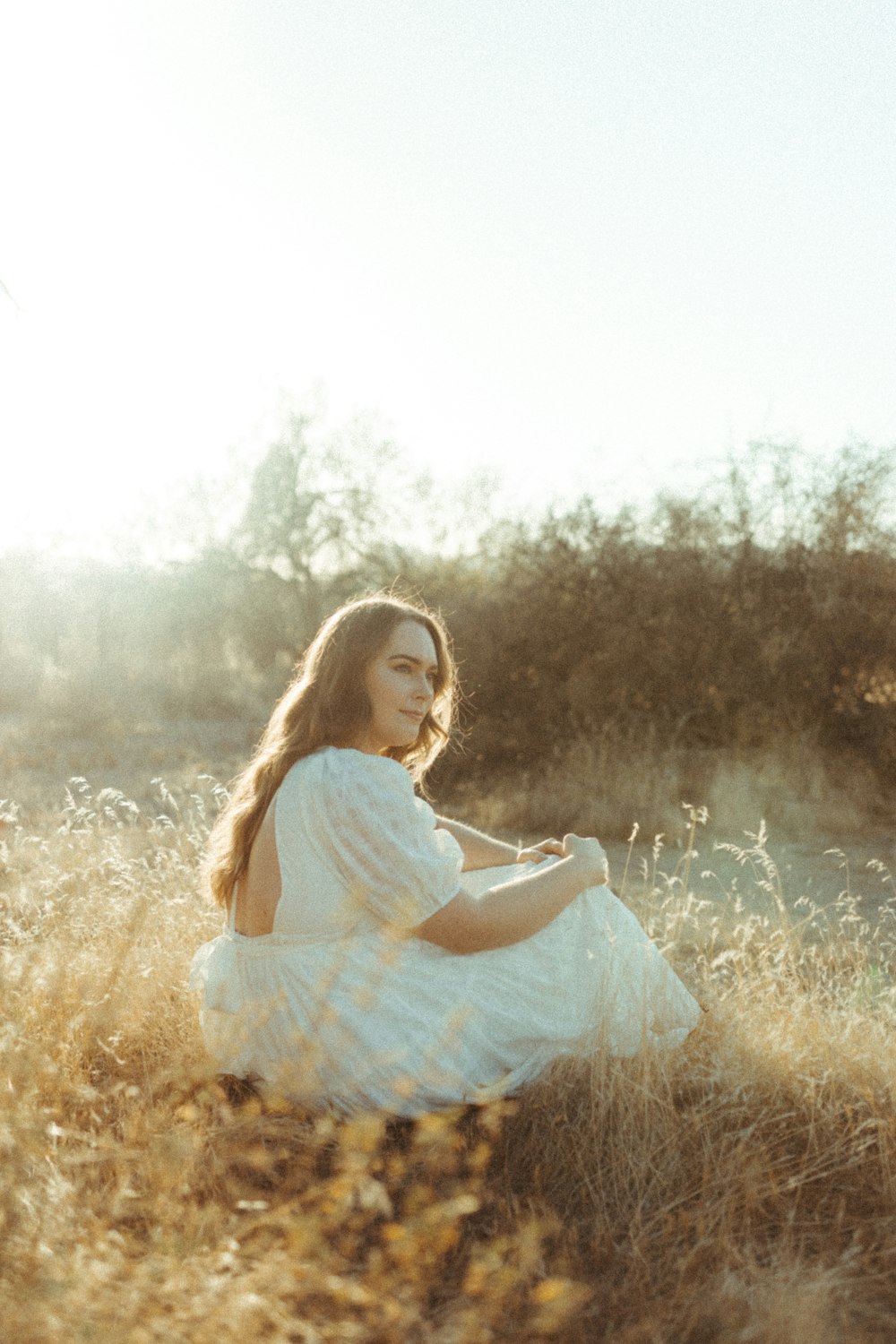 girl in white and blue stripe dress sitting on brown grass field during daytime