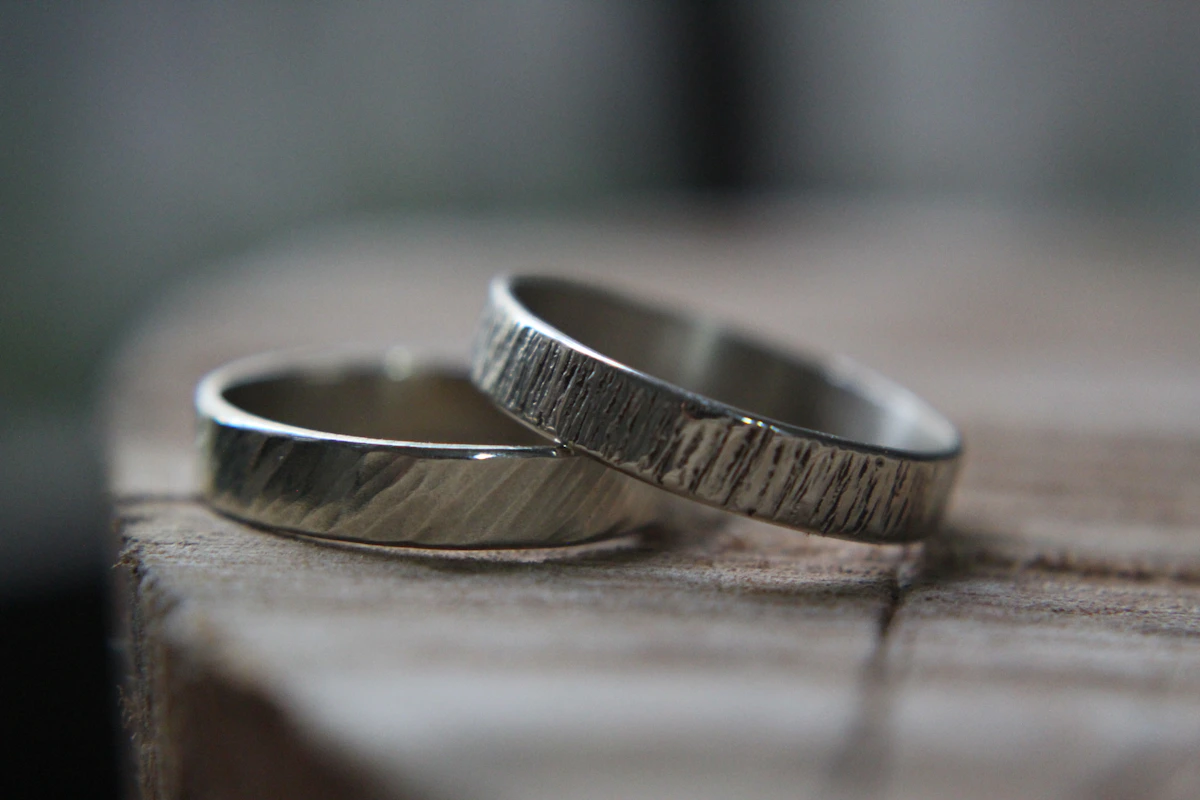 Hands wearing a handmade silver wedding band showing the polished finish