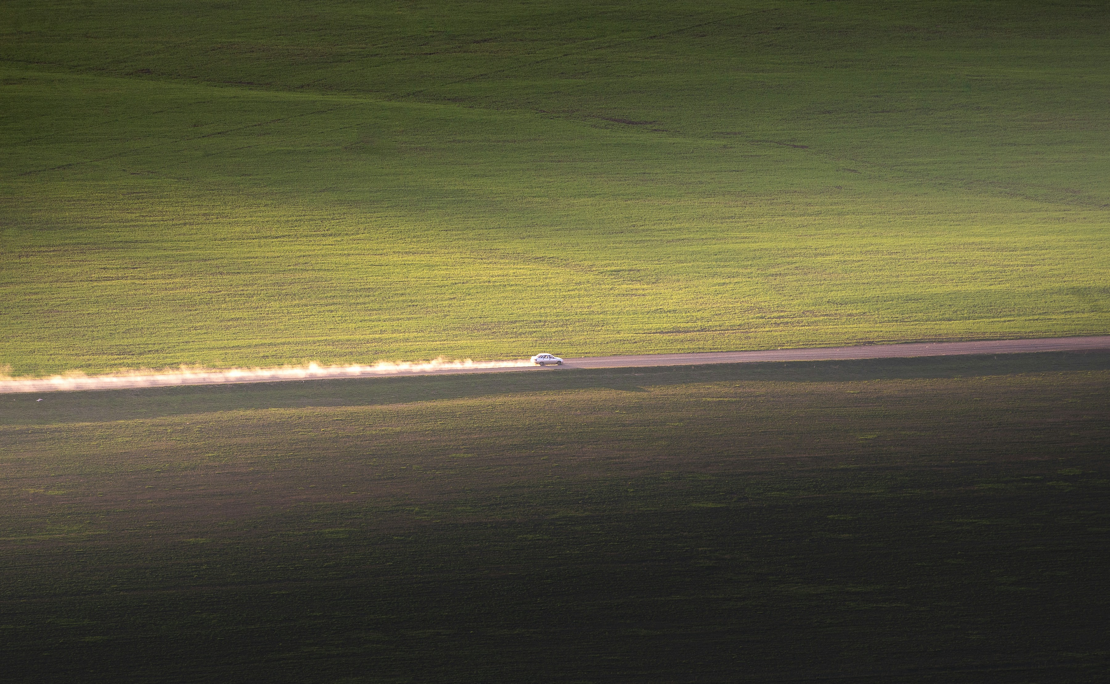 A photo of a car moving along a country road