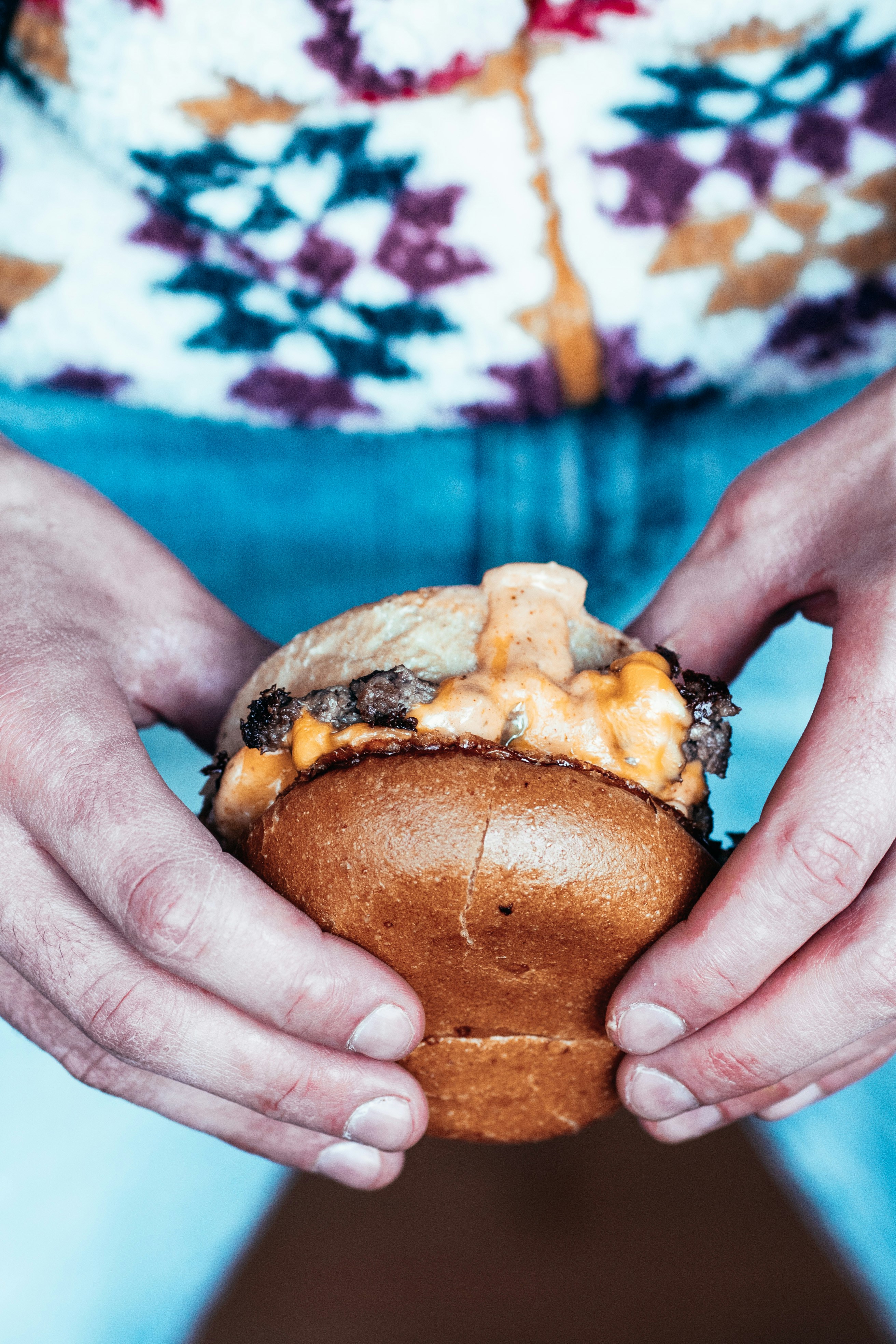 person holding burger with cheese