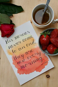 A serene flat lay of colorful affirmation cards scattered on a wooden table with a cup of tea nearby