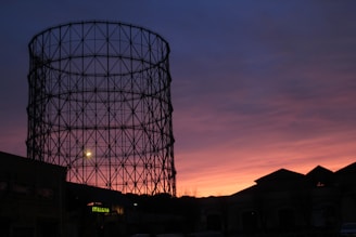 Sunset view of a Sheild Gas Systems facility with gas tanks silhouetted against the sky.