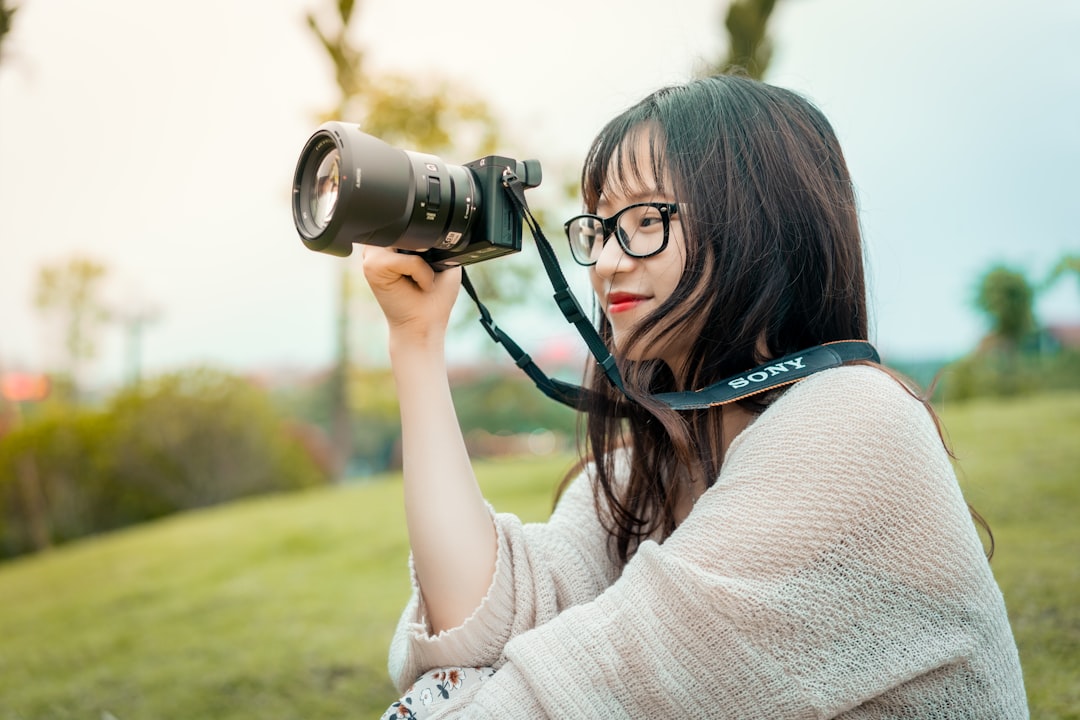 woman in white sweater holding black dslr camera