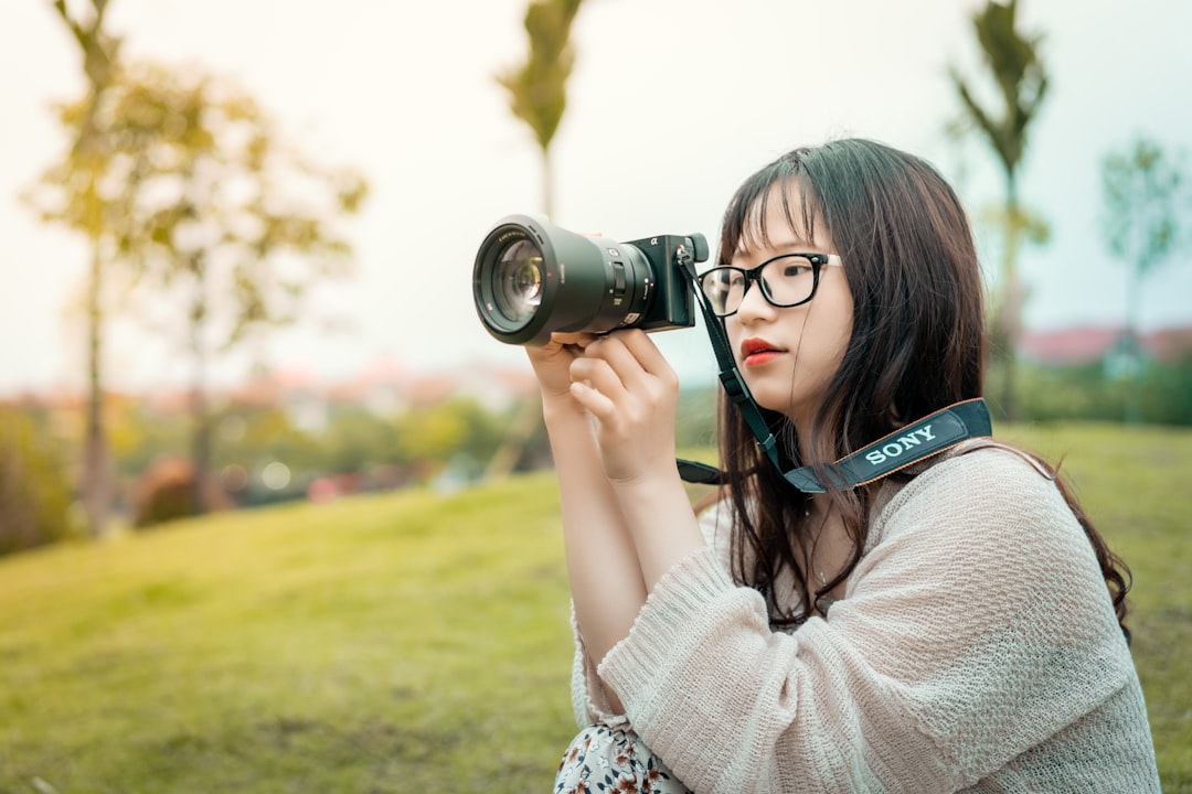 woman in gray sweater holding black dslr camera during daytime