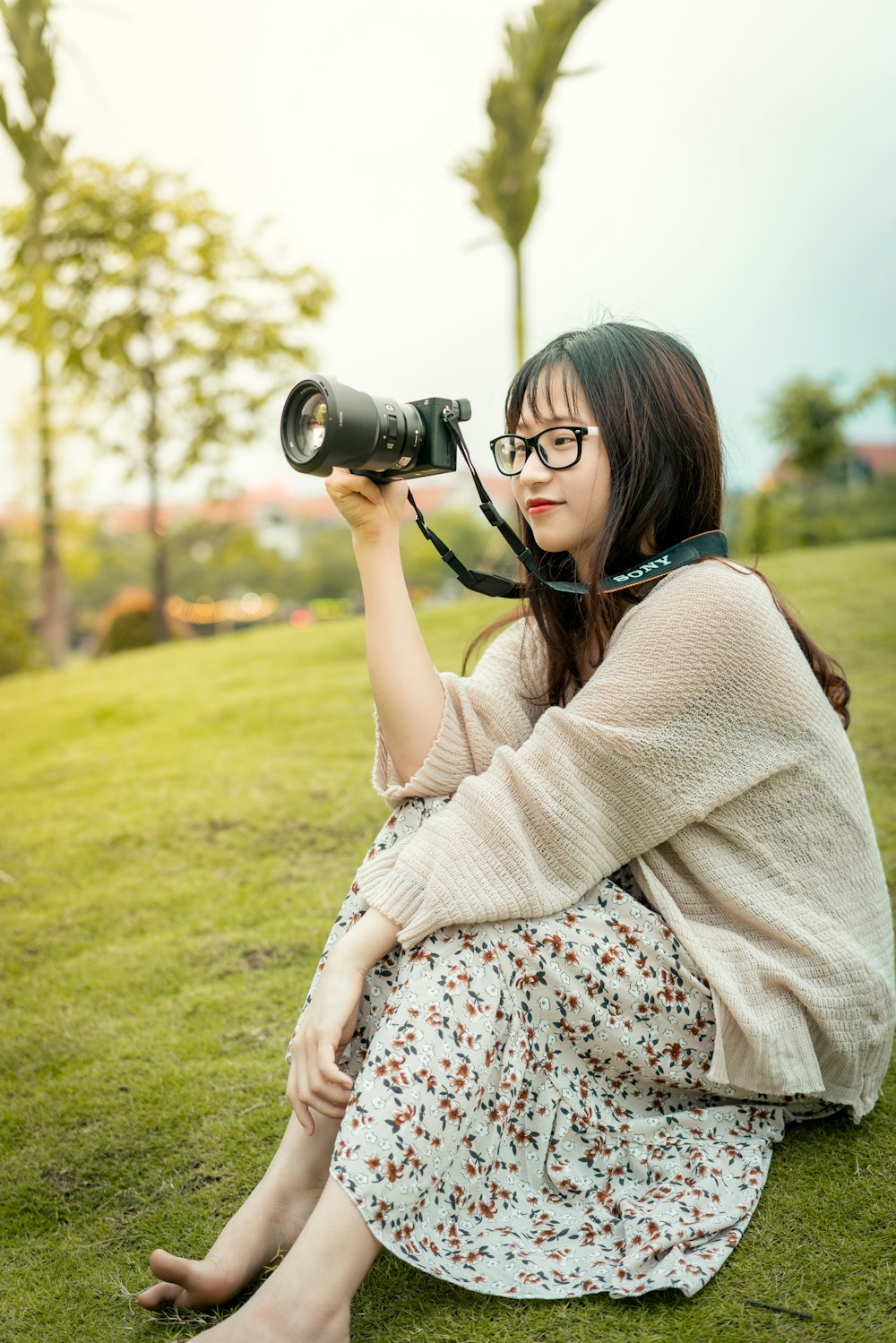 woman in brown and white floral dress holding black dslr camera