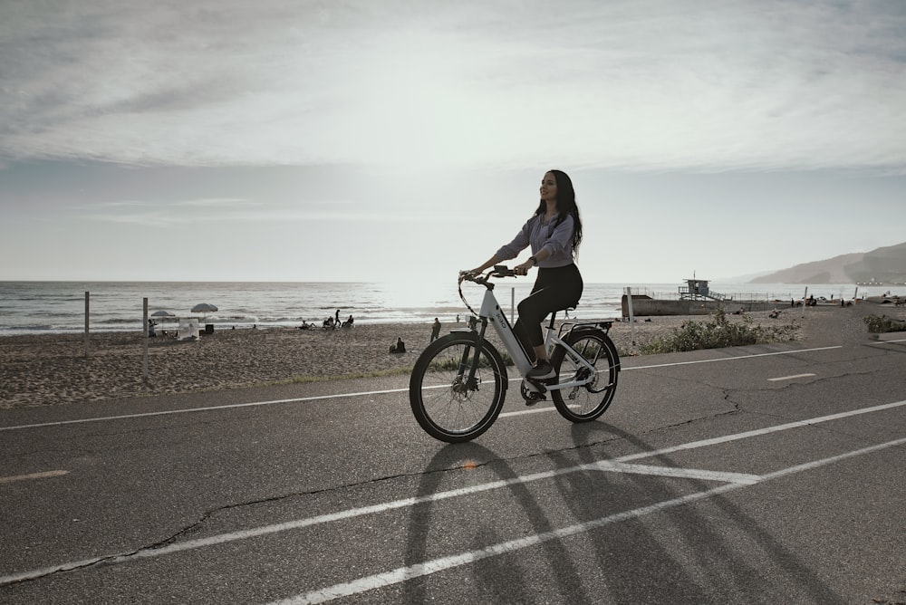 Mujer en camisa negra de manga larga montando en bicicleta en carretera de asfalto gris durante el día