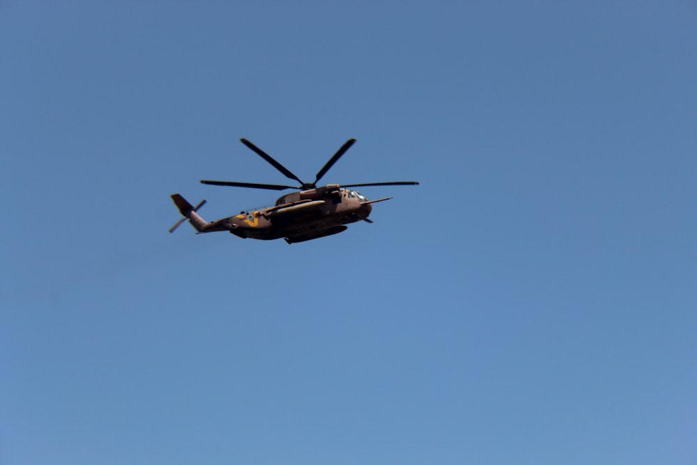 Schwarz-brauner Hubschrauber fliegt am Himmel