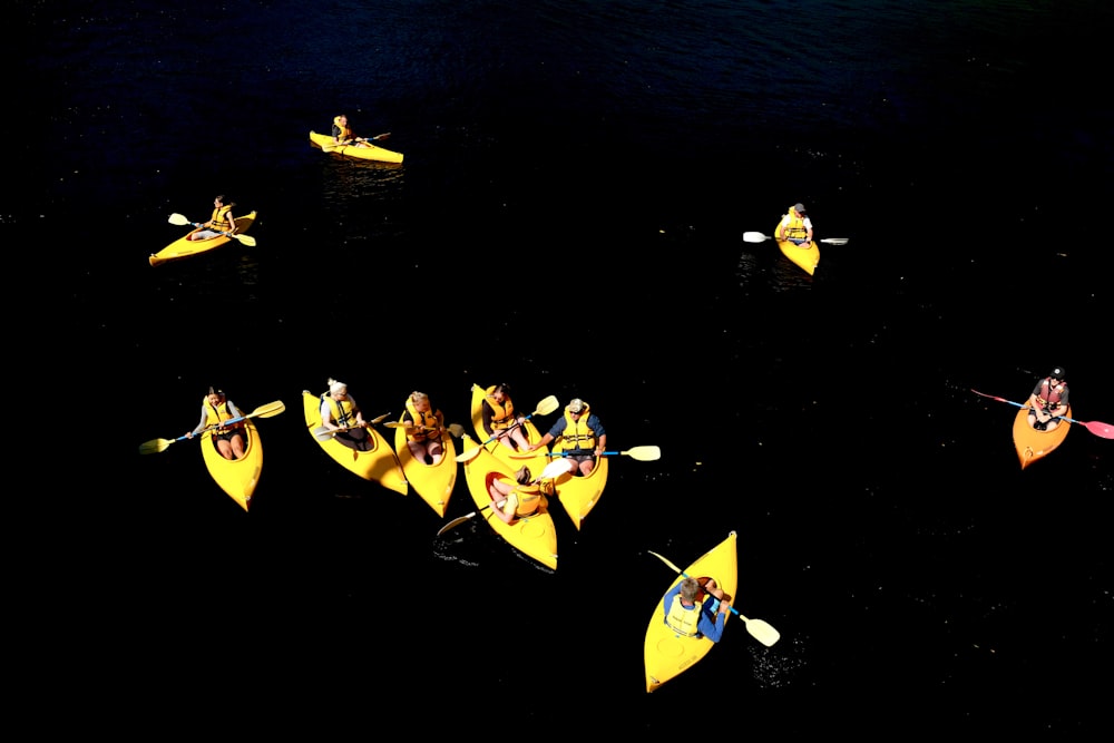 people riding yellow and blue kayaks on body of water during daytime