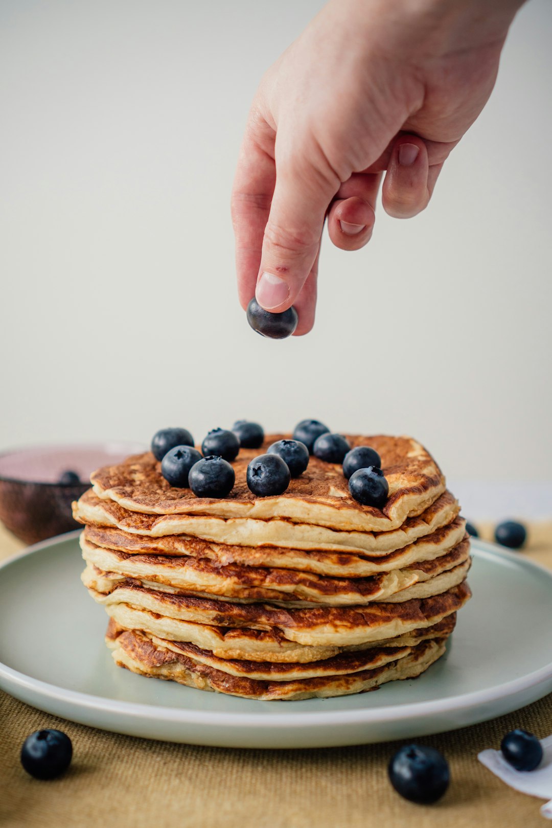 person holding a plate of pancakes with black berries
