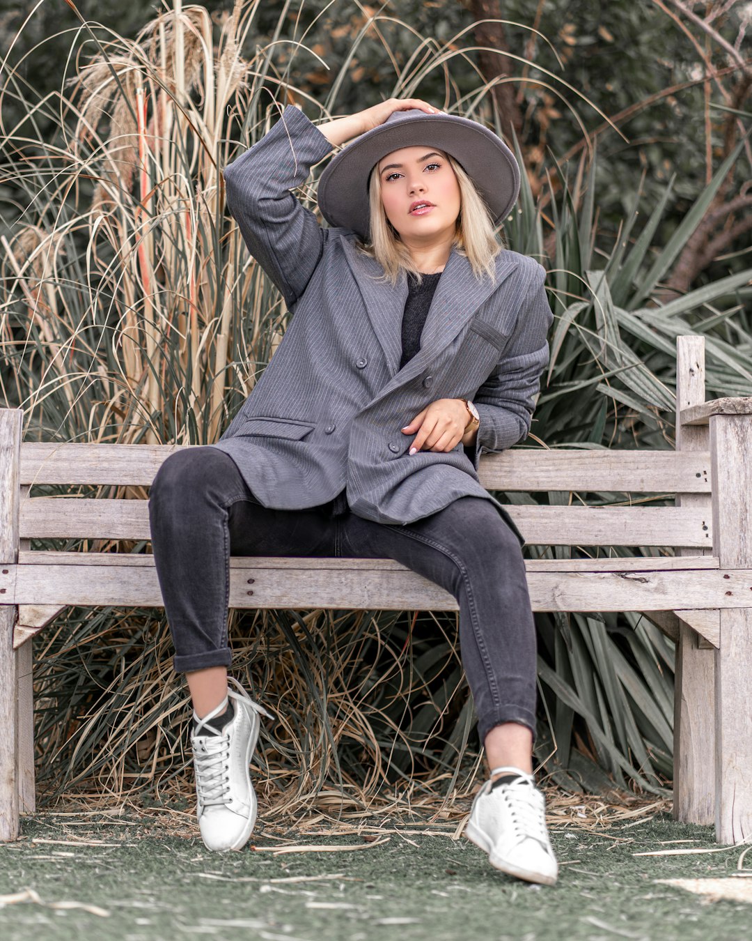 woman in gray coat sitting on brown wooden bench