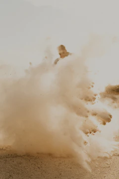 Dynamic action scene with gunfire and dust clouds in western setting.
