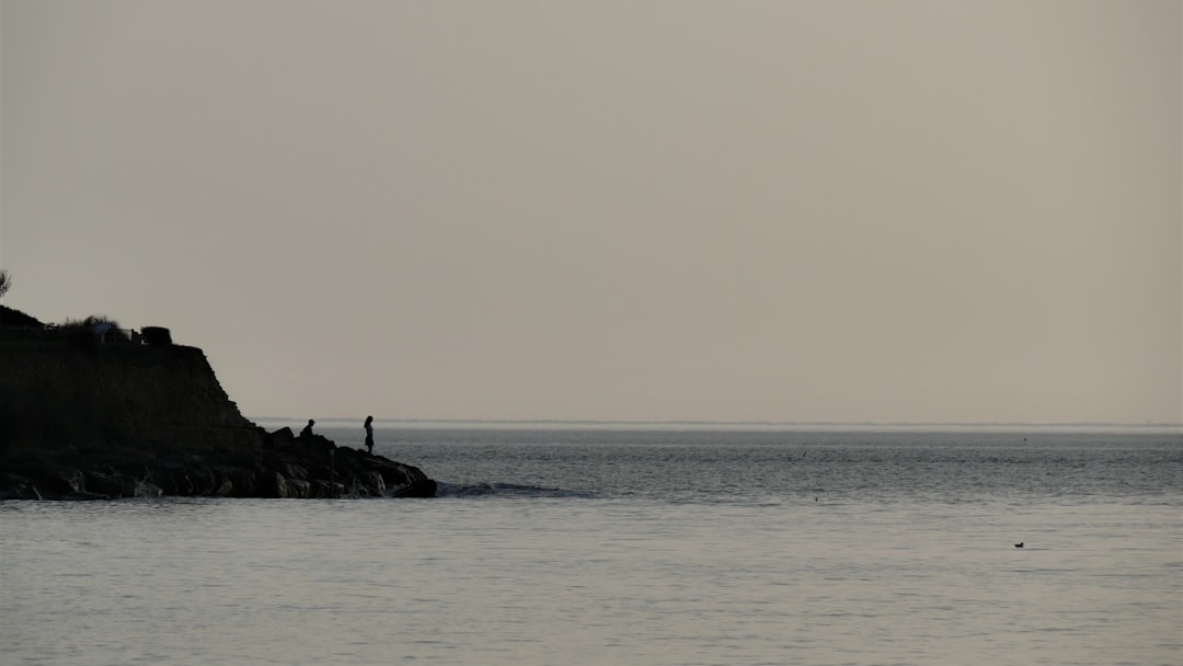 person standing on rock formation in the middle of sea