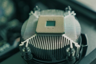 A central processing unit (CPU) with a visible grid of pins is placed on top of a metallic heat sink with radial fins, surrounded by mounting screws.