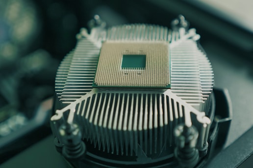 A central processing unit (CPU) with a visible grid of pins is placed on top of a metallic heat sink with radial fins, surrounded by mounting screws.
