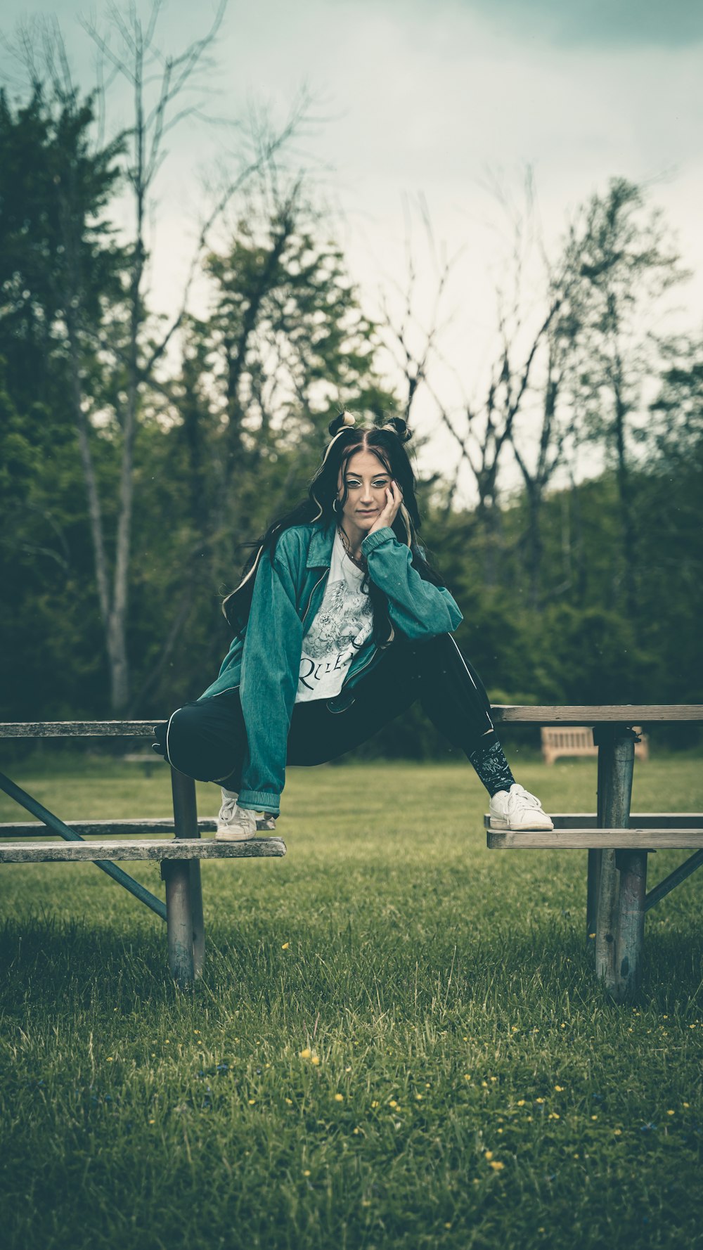woman in blue long sleeve shirt and black pants sitting on brown wooden bench