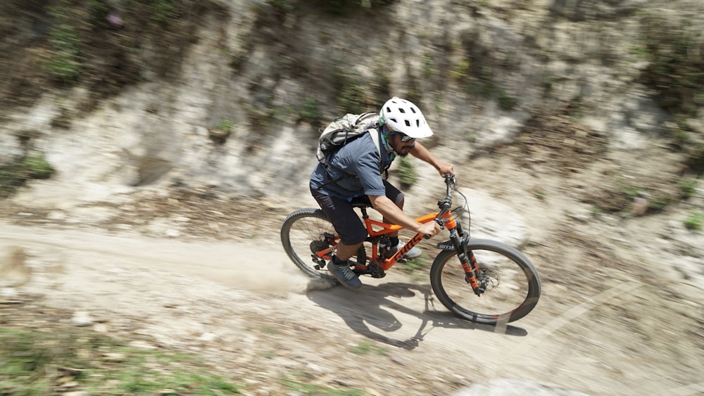 man in blue jacket riding orange bmx bike on a dirt trail