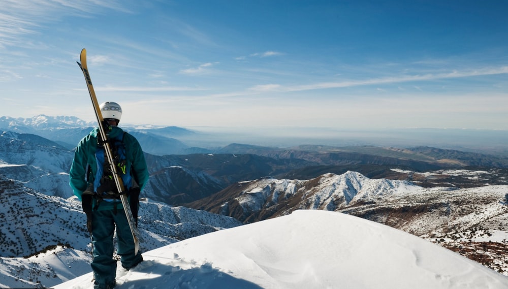 man in green jacket standing on snow covered mountain during daytime