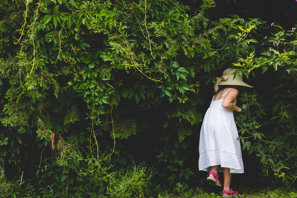 woman in white dress standing near green trees during daytime