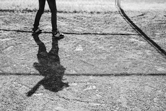 grayscale photo of person walking on field