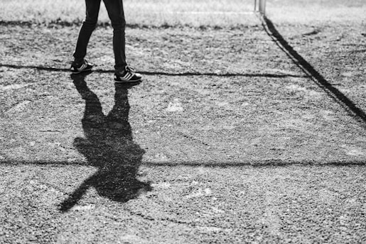 grayscale photo of person walking on field