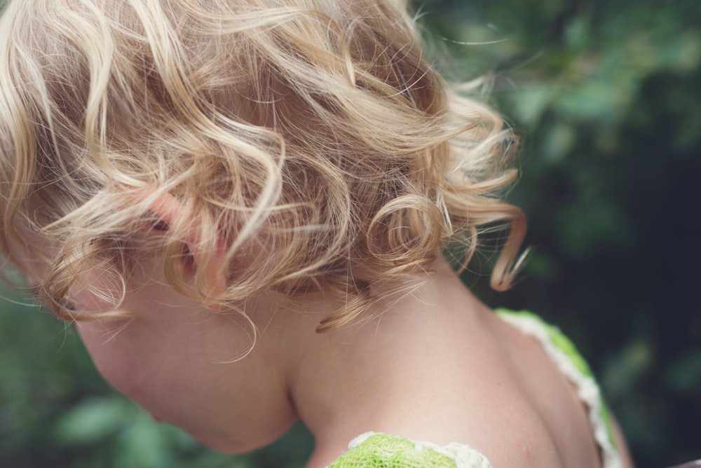 woman with blonde hair holding green leaf