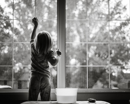 menina de pijama de costas para a câmera e limpando janela