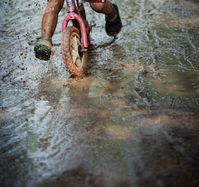 girl in pink and black bicycle on wet ground