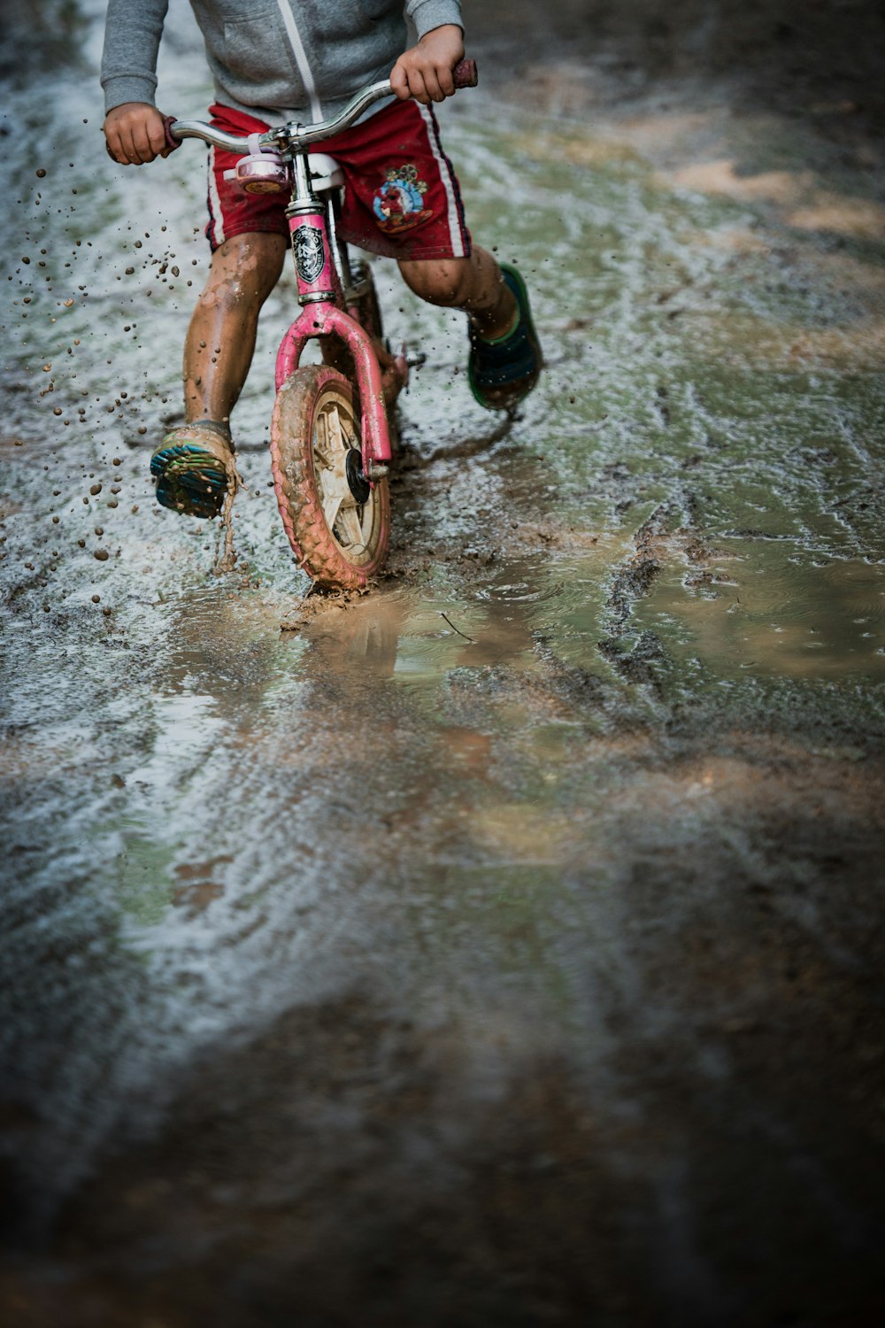 젖은 땅에 분홍색과 검은 자전거를 탄 소녀