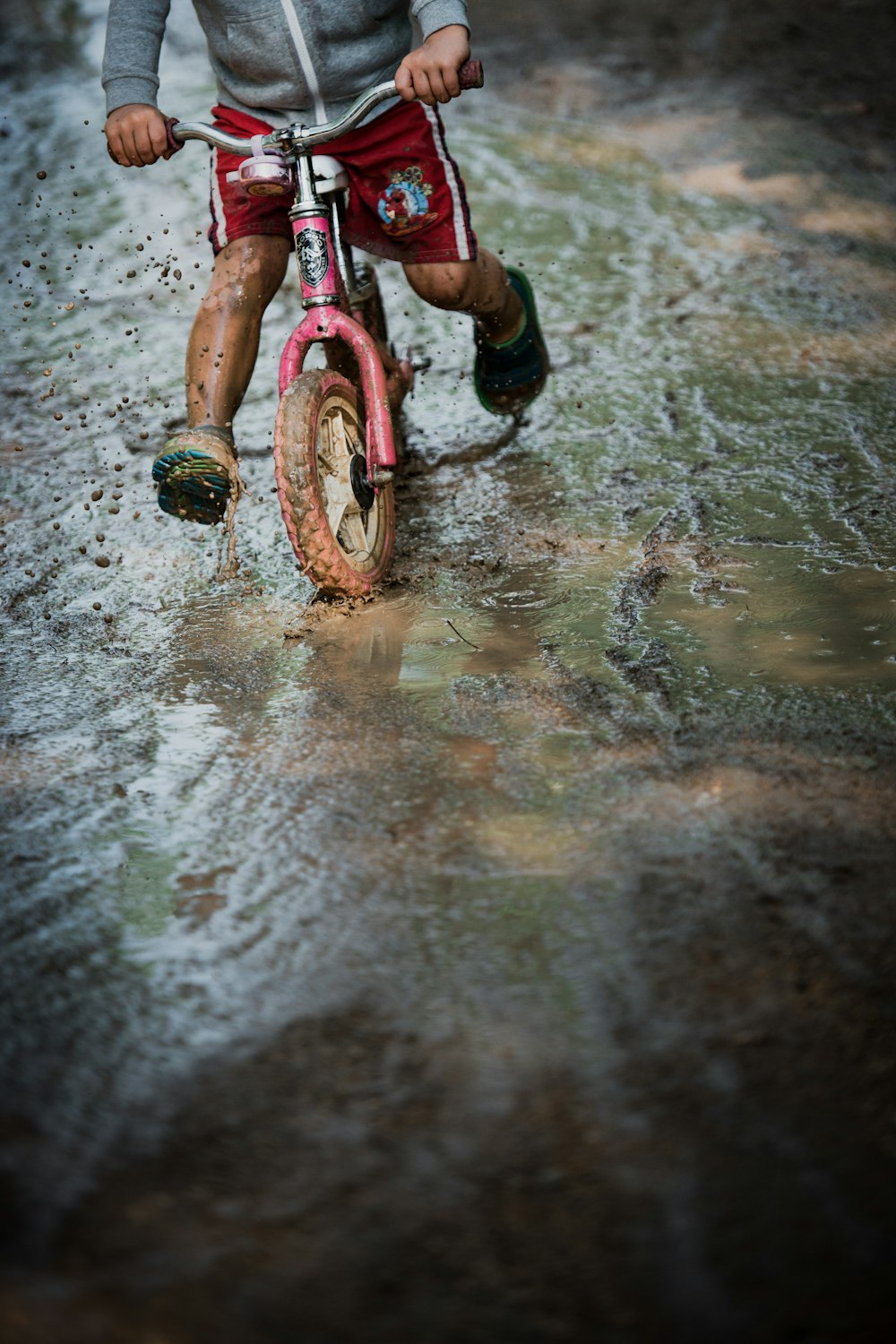 Muchacha en bicicleta rosa y negra en suelo mojado