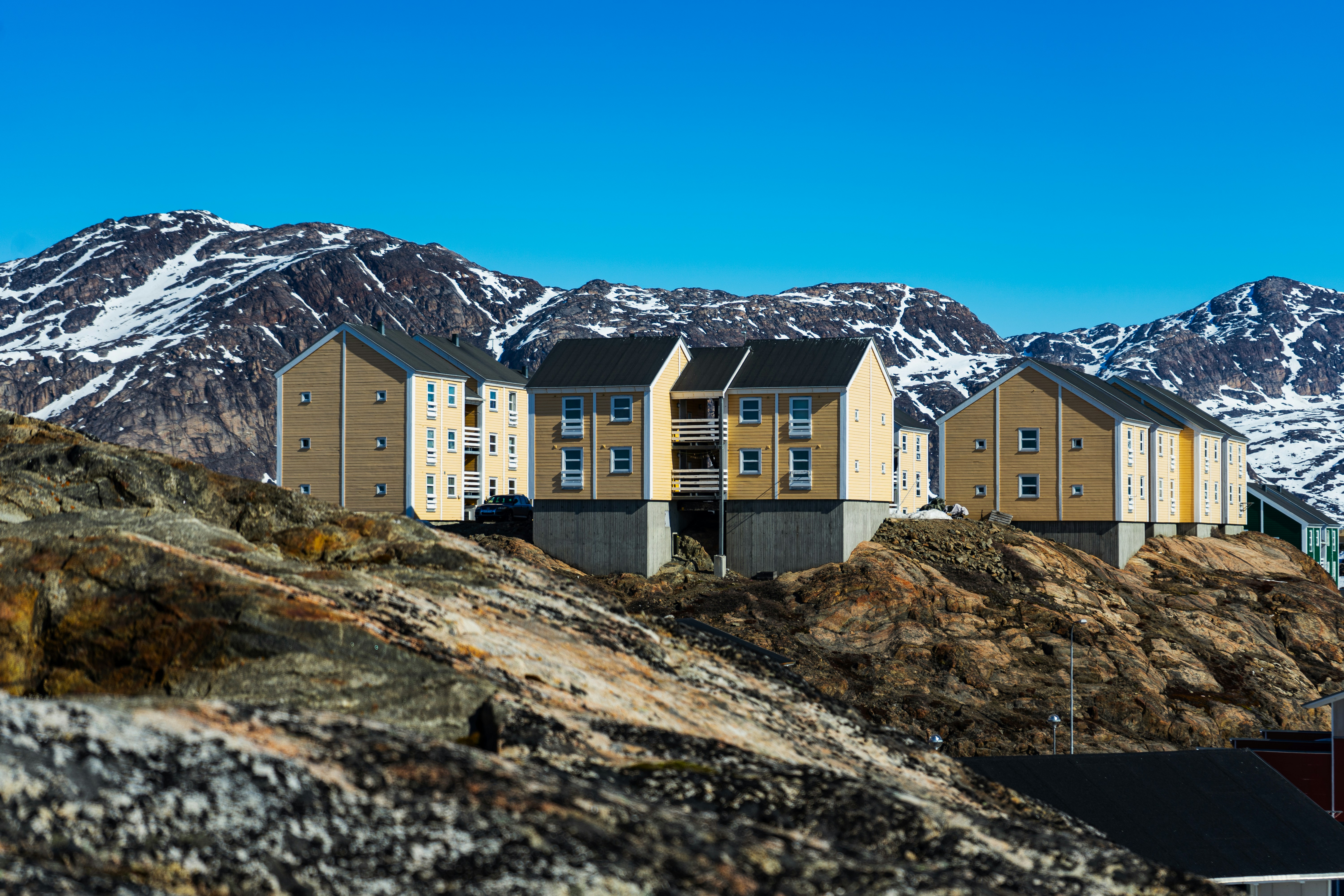 white and brown concrete building near mountain under blue sky during daytime