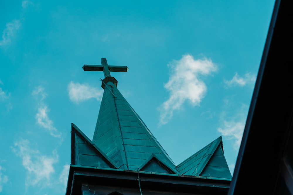 昼間の青空の下、ビルの屋上に黒い十字架