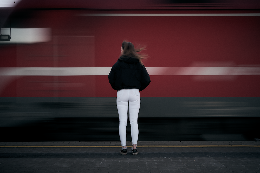 woman in black long sleeve shirt and white pants standing on sidewalk