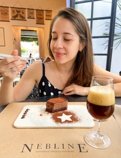 A lifestyle shot of a stylish woman savoring a slice of marova patisserie cake in a chic black and rose gold cafe setting.