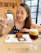A smiling woman enjoying a slice of chocolate cake at a cozy bakery table.