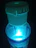 A close-up of a Mind Effect bottle with gold, sea blue, and purple accents glowing softly.