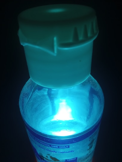 A close-up of a glowing potion bottle emitting a soft blue light on a wooden table.